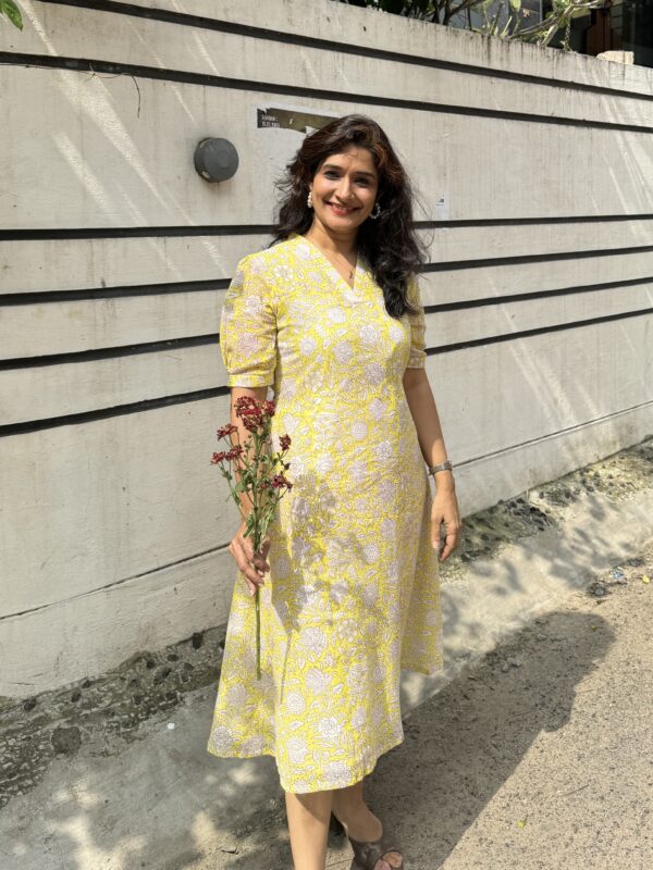 A girl in yellow dress in block printed cotton posing with flowers